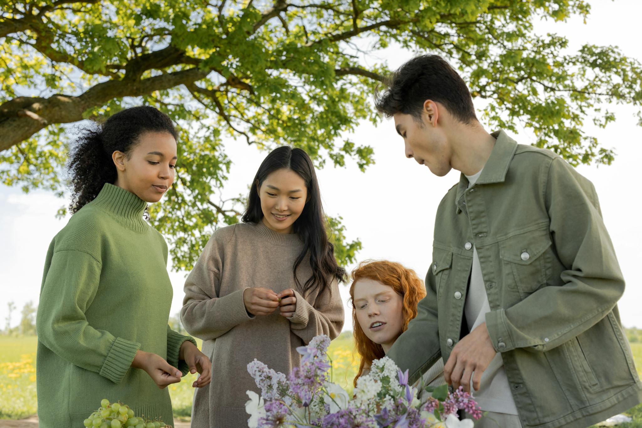 Group of diverse friends enjoying a spring day outdoors, sharing smiles and flowers.